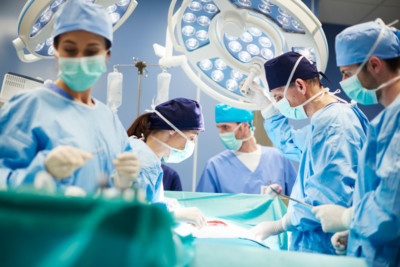 Two surgeons in an operating room with three other medical team members