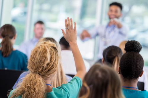 Woman raising her hand to ask a question at a Sales Force training Session 
